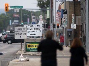 People walk towards signs for a drive through COVID-19 testing site in Winnipeg on Tuesday, July 6, 2021.