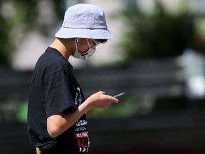 A person wears a mask while using a phone in a public place in Winnipeg on Friday, July 9, 2021.