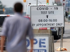 A person walks near a sign for a Covid-19 test site in Winnipeg, in Winnipeg.  Tuesday, July 13/2021.Winnipeg Sun/Chris Procaylo/stf