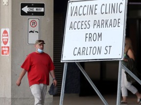 A person were a mask while walking past a sign for a vaccine clinic in Winnipeg 
 on Wednesday, July 14, 2021.