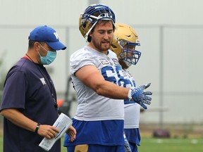 Offensive lineman Geoff Gray (centre) speaks with position coach Marty Costello at Winnipeg Blue Bombers training camp on the University of Manitoba campus in Winnipeg on Monday, July 19, 2021. Gray has re-signed with the Bombers for another two years.