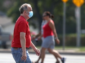 A person wears a mask while crossing a street in Winnipeg on Saturday, July 24, 2021.
