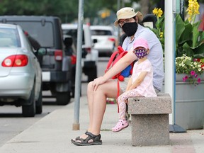 A father and daughter are masked up as they wait for a bus on Corydon Avenue in Winnipeg on Monday, July 26, 2021.