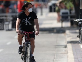 A person wears a mask while cycling through downtown Winnipeg on Saturday, July 31, 2021.