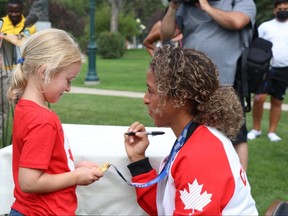 Kennedy Lopuck, 6, checks out Desiree Scott's gold medal at the Manitoba Legislature in Winnipeg on Thursday, Aug. 19, 2021. Josh Aldrich/Winnipeg Sun