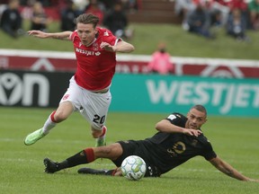 Cavalry FC Joe Mason (left) is tackled by Valour FC Rocco Romeo during CPL soccer action between Valour FC and Cavalry FC in Calgary at ATCO Field on Sunday, August 8, 2021.