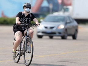 A person wears a mask while riding a bicycle in Winnipeg on Wednesday afternoon. Chris Procaylo/Winnipeg Sun