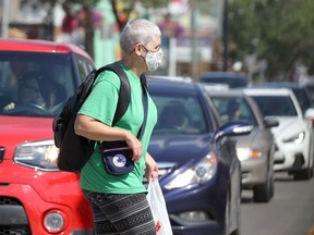 A woman wearing a mask crosses Corydon Avenue in Winnipeg on Tuesday, Aug. 31, 2021.