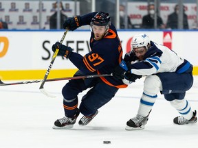 Edmonton Oilers captain Connor McDavid (97) battles Winnipeg Jets’ Dylan DeMelo (2) during the first period of their NHL North Division playoff series at Rogers Place in Edmonton on Wednesday, May 19, 2021.