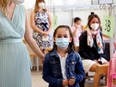 Children and parents wearing protective face masks wait for a COVID-19 rapid antigen test in a primary school, as Austrian schools open for pupils after summer holidays, in Vienna, Austria, Monday, Sept. 6, 2021.