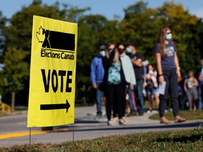 People line up outside a polling station to vote in the federal election in Bowmanville, Ontario, September 20, 2021.