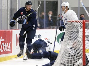 Brenden Dillon (left) draws a reaction from Adam Lowry (right) after his hit on Kristian Vesalainen also knocked down Ville Heinola during the first day of Winnipeg Jets training camp in Winnipeg on Sept. 23, 2021.