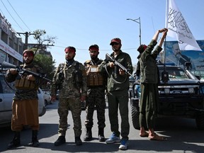 Taliban fighters stand guard along a road in Kabul on Thursday, Sept. 9, 2021.