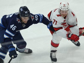 Winnipeg Jets forward Joona Luoto (left) and Carolina Hurricanes centre Lucas Wallmark battle for the puck in Winnipeg on Tuesday, Dec. 17, 2019.