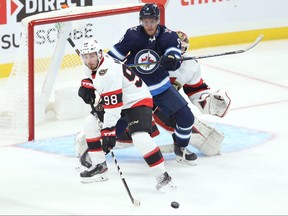 Winnipeg Jets forward Andrew Copp (centre) tries to create room for himself in front of Ottawa Senators goaltender Anton Forsberg by pushing defenceman Victor Mete as the shot comes during NHL exhibition play at Canada Life Centre in Winnipeg on Sunday, Sept. 26, 2021.