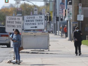 People pass by signs for a COVID-19 test site in Winnipeg on Tuesday, Sept. 28, 2021.