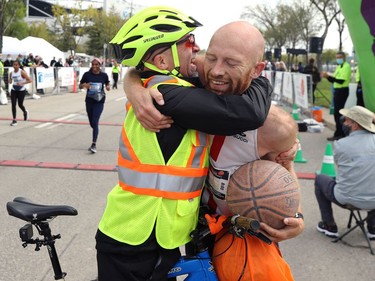 Steffan Reimer (right), who is believed to have set a world record for fastest marathon while dribbling a basketball, is hugged after bouncing across the finish line of the 2021 Manitoba Marathon in Winnipeg on Sunday, Sept. 5, 2021.