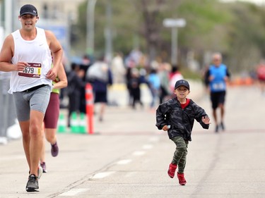 Scott Lavallee (left) is joined by son Jeremiah, 5, as he finishes his half marathon at the Manitoba Marathon in Winnipeg on Sunday, Sept. 5, 2021.