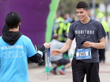 Nathan Moran from Gillam, Man., collects his finisher medal after running the 10-kilometre event as part of the Manitoba Marathon in Winnipeg on Sunday, Sept. 5, 2021.