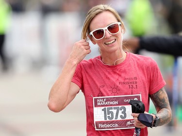 Rebecca Sturgess removes her earphones after crossing the finish line of her half marathon at the Manitoba Marathon in Winnipeg on Sunday, Sept. 5, 2021.