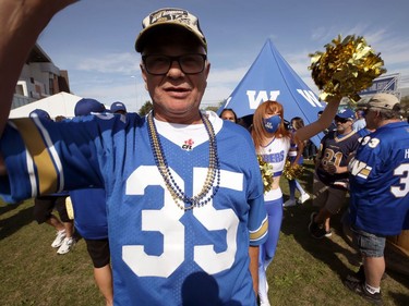 A fan winds up the head cheerleader in the tailgate area ahead of the Banjo Bowl battle between the Winnipeg Blue Bombers and Saskatchewan Roughriders in Winnipeg on Saturday, Sept. 11, 2021.