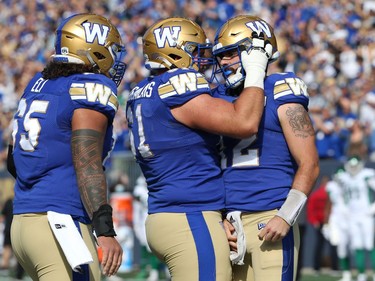Winnipeg Blue Bombers QB Sean McGuire (right) celebrates his rushing touchdown against the Saskatchewan Roughriders during the Banjo Bowl in Winnipeg with OL Asotui Eli (left) and Drew Desjarlais on Saturday, Sept. 11, 2021.