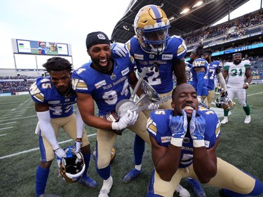 DeAundre Alford, Jackson Jeffcoat, Jonathan Kongbo, and Tobi Antigua (from left) of the Winnipeg Blue Bombers celebrate with the Banjo Bowl trophy after beating the Saskatchewan Roughriders in Winnipeg on Saturday, Sept. 11, 2021.