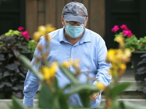 A man wearing a mask is framed by flowers as he walks out of a business on Corydon Avenue in Winnipeg on Wed., Sept. 15, 2021. KEVIN KING/Winnipeg Sun/Postmedia Network