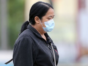 A woman wearing a mask crosses Portage Avenue in Winnipeg on Monday, Sept. 20, 2021.