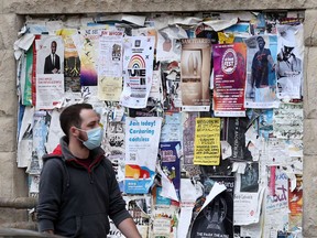 A person wears a mask while walking past posters on a wall, in Winnipeg on Thursday, September 22, 2021.