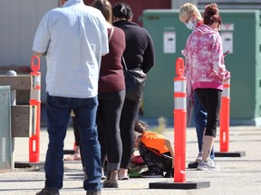 Children busy themselves on the concrete while people wait in line at a COVID-19 testing site on Portage Avenue in Winnipeg on Mon., Sept. 13, 2021. KEVIN KING/Winnipeg Sun/Postmedia Network