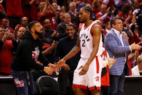 Kawhi Leonard of the Toronto Raptors high fives rapper Drake during game four of the NBA Eastern Conference Finals between the Milwaukee Bucks and the Toronto Raptors on May 21, 2019.
