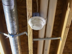 A smoke detector on the ceiling in a basement of a residential home