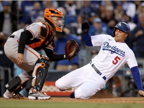 Corey Seager #5 of the Los Angeles Dodgers scores against Buster Posey #28 of the San Francisco Giants on a double by Trea Turner #6 during the first inning in game 4 of the National League Division Series at Dodger Stadium on October 12, 2021 in Los Angeles, California.