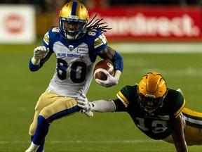 Edmonton Elks’ Shaydon Philip (13) reaches for Winnipeg Blue Bombers’ Janarion Grant (80) during second half CFL football action at Commonwealth Stadium in Edmonton, on Friday, Oct. 15, 2021.