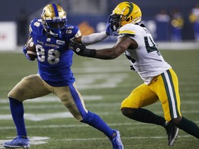 Bombers’ Rasheed Bailey makes the first down against Edmonton Elks’ Keishawn Bierria at IG Field in Winnipeg last night. The Bombers won 30-3. John Woods/The Canadian Press