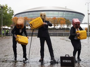 Ocean Rebellion activists wear oil cannister masks as they spill fake oil in front of the venue for COP26 in Glasgow, Scotland, Oct. 29, 2021.