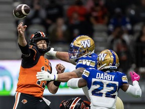 B.C. Lions quarterback Michael Reilly is hit by Winnipeg Blue Bombers' Casey Sayles as he passes while Alden Darby watches during the first half at B.C. Place on Friday night.