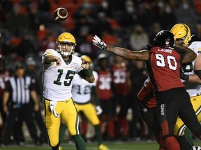 Edmonton Elks quarterback Taylor Cornelius (15) throws the ball past the arm of Ottawa Redblacks defensive lineman Cleyon Laing (90) in Ottawa on Sept. 28, 2021.