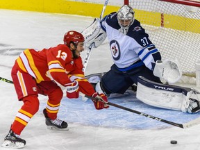 Winnipeg Jets goalkeeper Connor Hellebuyck makes a save against Johnny Gaudreau of the Calgary Flames during an NHL pre-season game at Scotiabank Saddledome on Oct. 8, 2021.