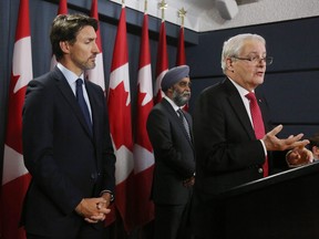 Prime Minister Justin Trudeau and Minister of National Defence Harjit Sajjan listen as Minister of Transportation Marc Garneau addresses the media during a news conference Jan. 8, 2020 in Ottawa.