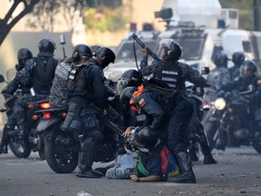An anti-government protester is detained by security forces during clashes with security forces in Caracas on the commemoration of May Day on May 1, 2019.