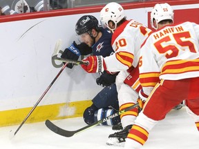 Winnipeg Jets forward Jansen Harkins (left) is driven into the boards by Calgary Flames forward Blake Coleman (centre) during preseason NHL action in Winnipeg on Wed., Oct. 6, 2021. KEVIN KING/Winnipeg Sun/Postmedia Network