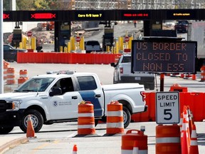 A U.S. Customs and Protection vehicle stands beside a sign reading that the border is closed to non-essential traffic at the Canada-United States border crossing at the Thousand Islands Bridge, in Lansdowne, Ont., Sept. 28, 2020.