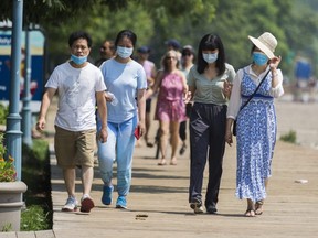 People wear masks along the boardwalk in The Beaches neighbourhood in Toronto, July 25, 2021.