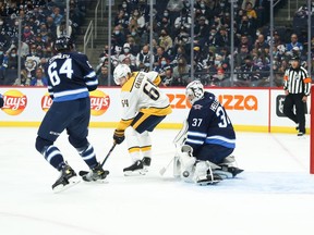 Winnipeg Jets goaltender Connor Hellebuyck (37) makes a save despite a screen by  Nashville Predators forward Mikael Granlund (64) during the first period at Canada Life Centre in Winnipeg on Oct. 23, 2021.