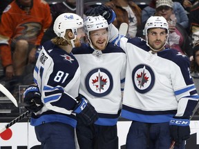 ANAHEIM, CALIFORNIA - OCTOBER 26: Dylan DeMelo #2 and Kyle Connor #81 congratulate Evgeny Svechnikov #71 of the Winnipeg Jets after his goal during the second period of a game against the Anaheim Ducks at Honda Center on October 26, 2021 in Anaheim, California.