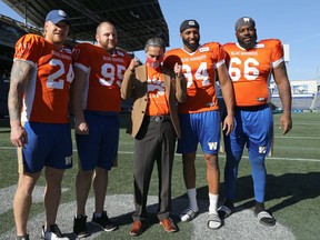 Arlen Dumas (centre), grand chief of the Assembly of Manitoba Chiefs, gives the thumbs up during a photo opp with Winnipeg Blue Bombers players (from left) Mike Miller, Jake Thomas, Jackson Jeffcoat and Stanley Bryant after a press conference at IG Field on Tuesday, Oct. 5, 2021 where the Bombers unveiled an orange warmup jersey both they and the Edmonton Elks will be wearing Friday in recognition of Orange Shirt Day.