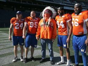 David Monias (centre), vice-chief of Manitoba Keewatinowi Okimakanak, has a photo opp with Winnipeg Blue Bombers players (from left) Mike Miller, Jake Thomas, Jackson Jeffcoat and Stanley Bryant after a press conference at IG Field on Tuesday, Oct. 5, 2021 where the Bombers unveiled an orange warmup jersey both they and the Edmonton Elks will be wearing Friday in recognition of Orange Shirt Day.