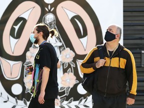 Men in masks on Portage Avenue in Winnipeg on Monday, Oct. 18, 2021.